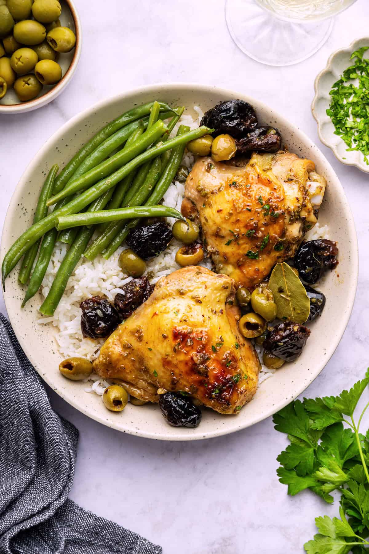 Overhead view of chicken marbella on plate with rice and green beans