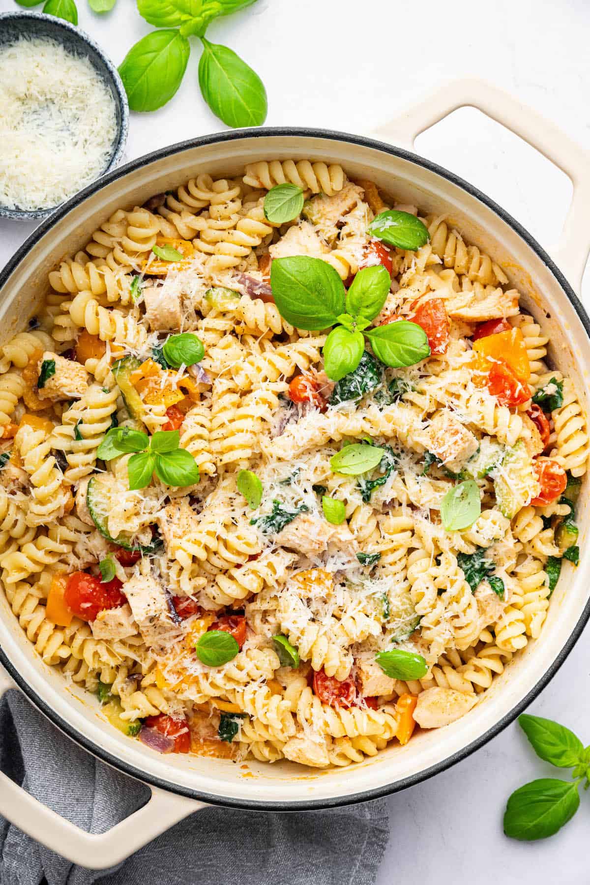Healthy chicken pasta primavera in pot with Parmesan cheese on top