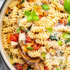 Overhead view of chicken pasta primavera in pot with wooden spoon