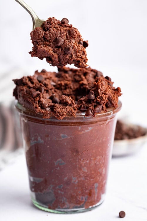 Spoonful of edible brownie batter held over jar
