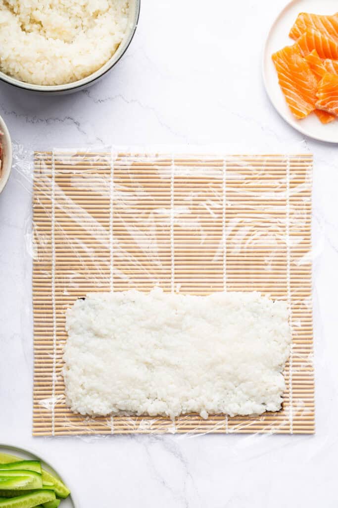 Overhead view of rice on sushi mat