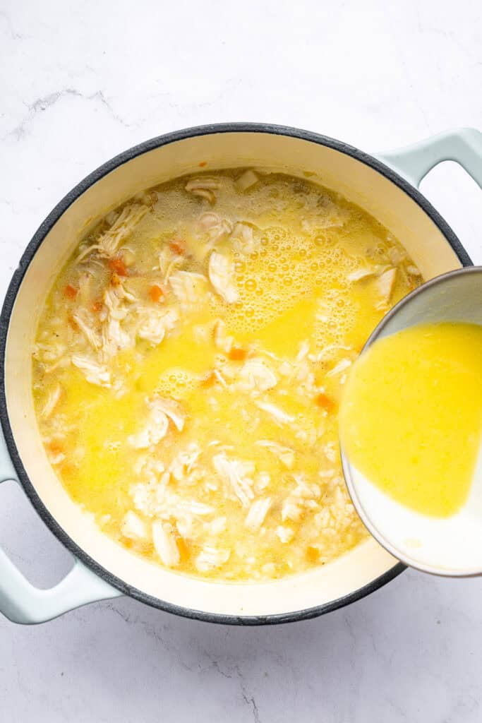 Pouring tempered eggs into pot of avgolemono soup