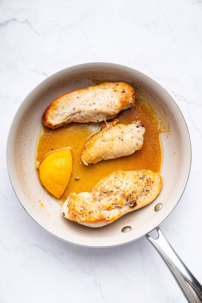 Overhead view of chicken breasts cooking in skillet