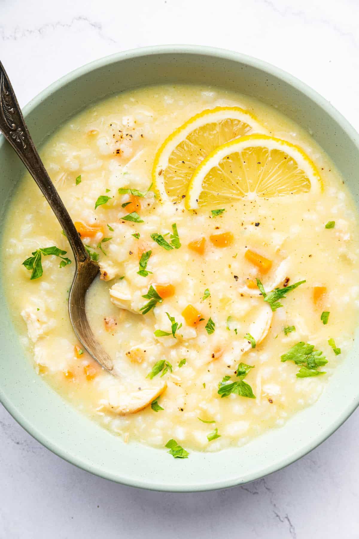 Avgolemono soup is a traditional Greek recipe known for its creamy texture and big, bright lemon flavor. It’s easy to make and so delicious! Bowl of avgolemono soup with fresh lemon slices