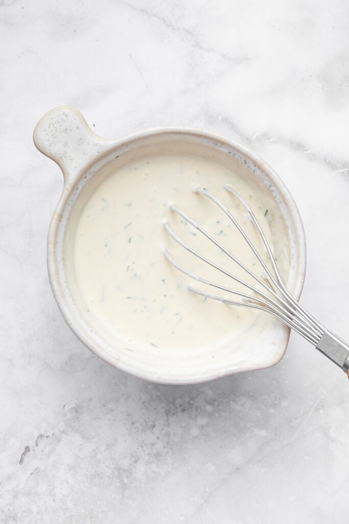 Whisk in bowl of creamy dill dressing
