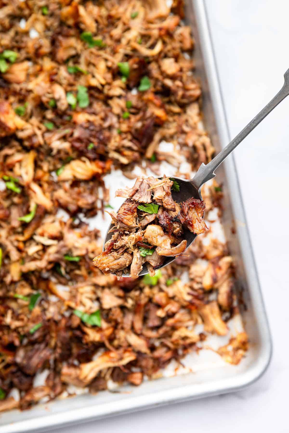 Overhead view of Instant Pot carnitas on sheet pan with serving spoon
