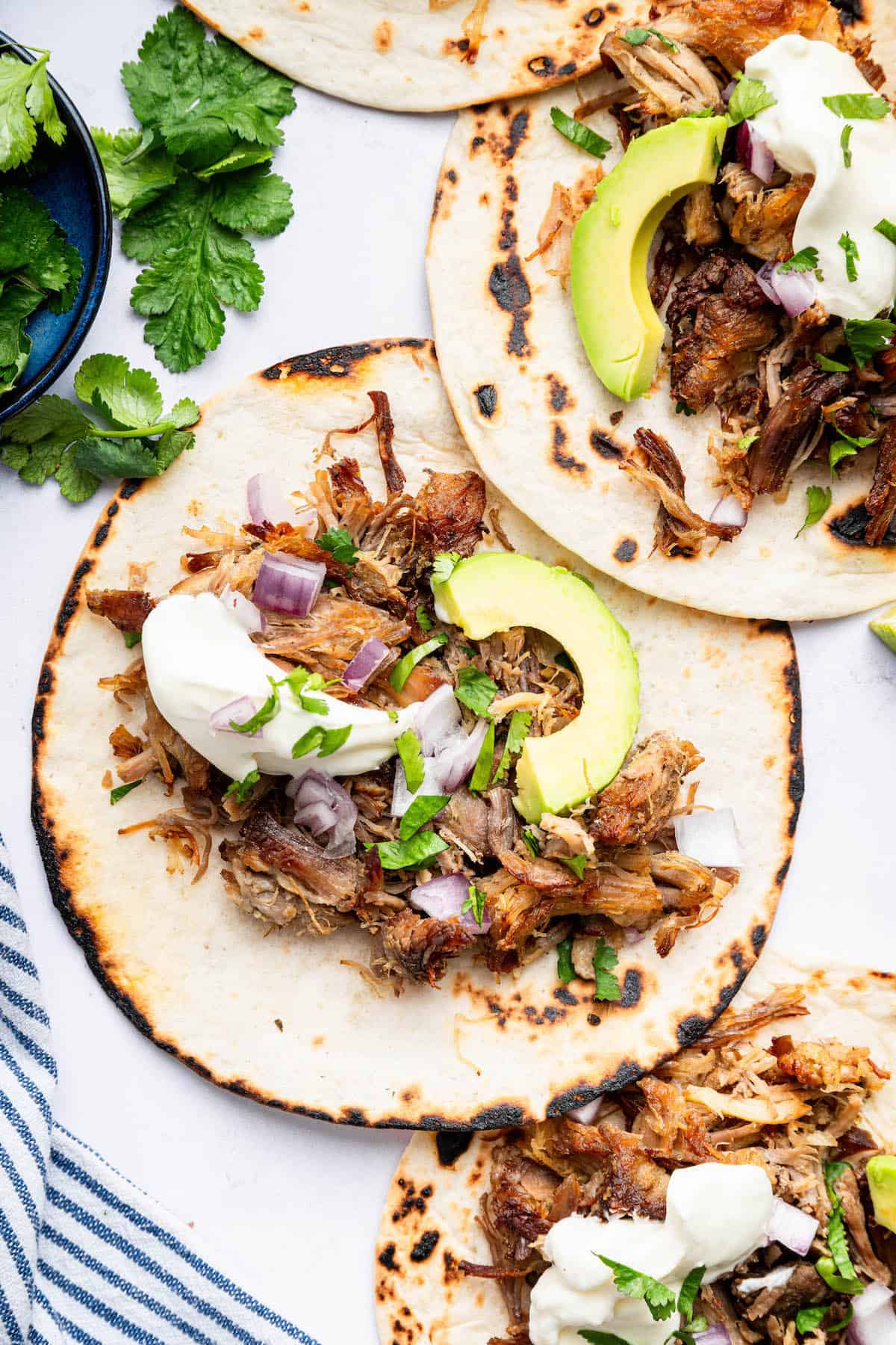Pork carnitas piled onto tortillas with toppings