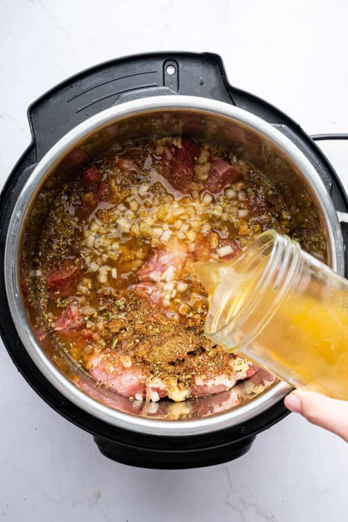 Pouring broth into Instant Pot with pork