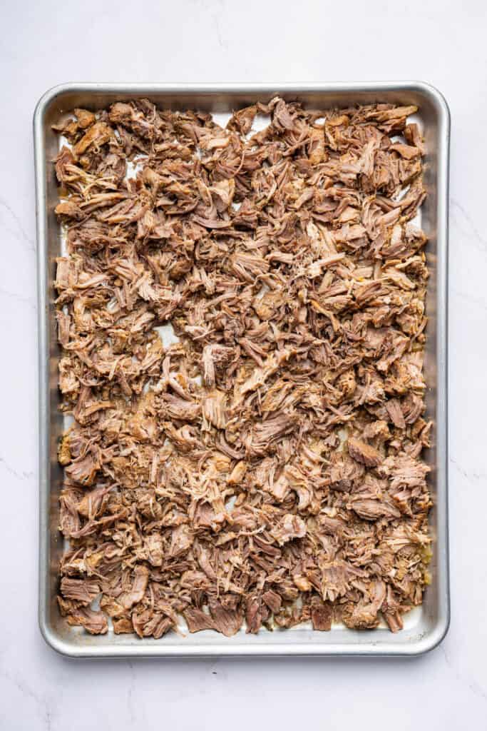 Overhead view of shredded Instant Pot carnitas on sheet pan before broiling