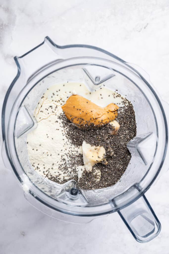 Overhead view of ingredients for peanut butter banana smoothie in blender