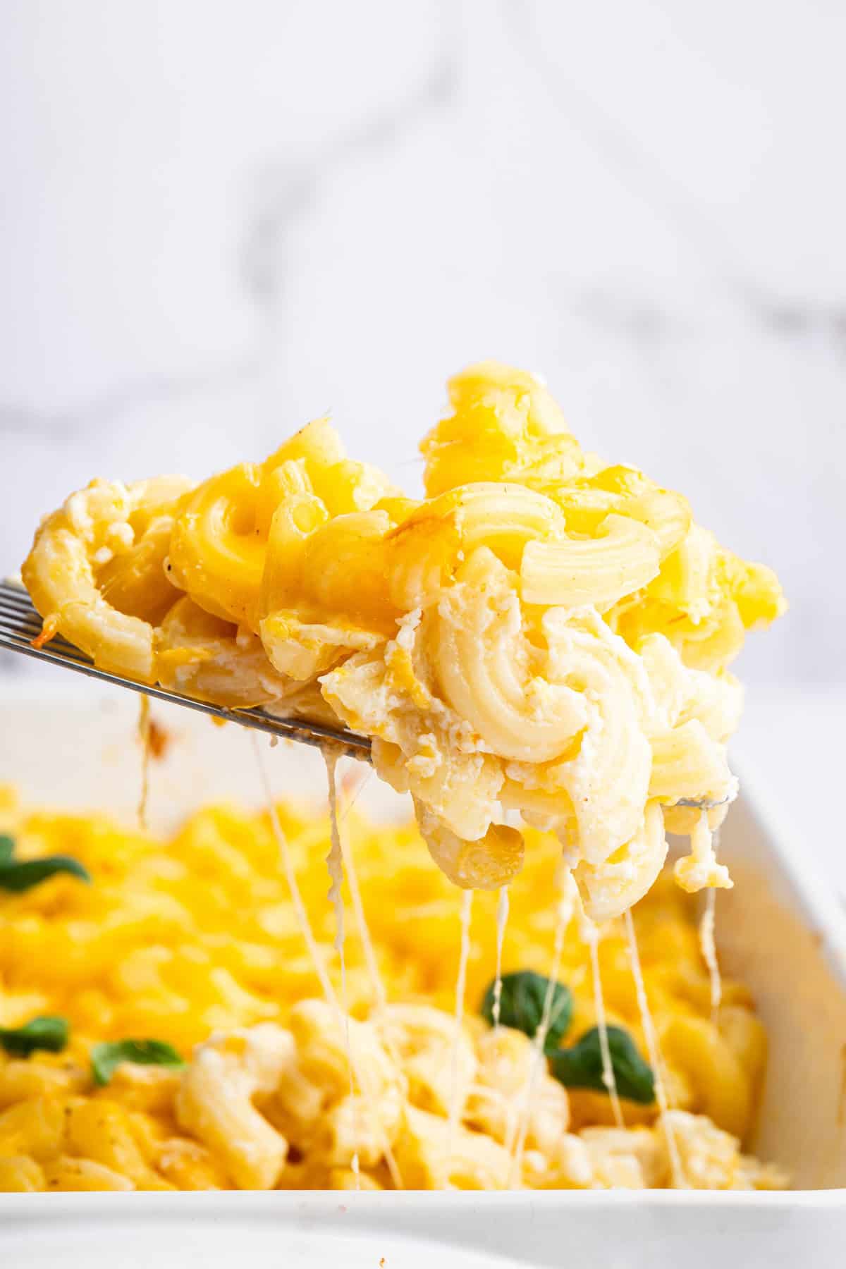 Spatula lifting protein mac and cheese from baking dish
