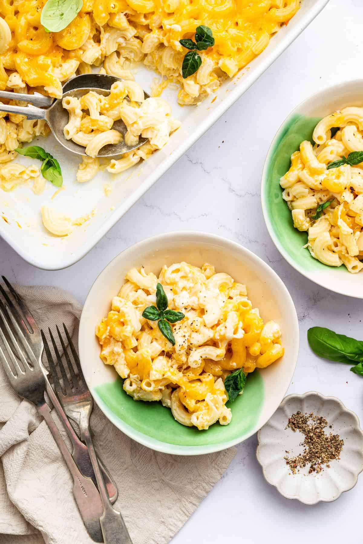 Overhead view of protein mac and cheese in two bowls and casserole dish