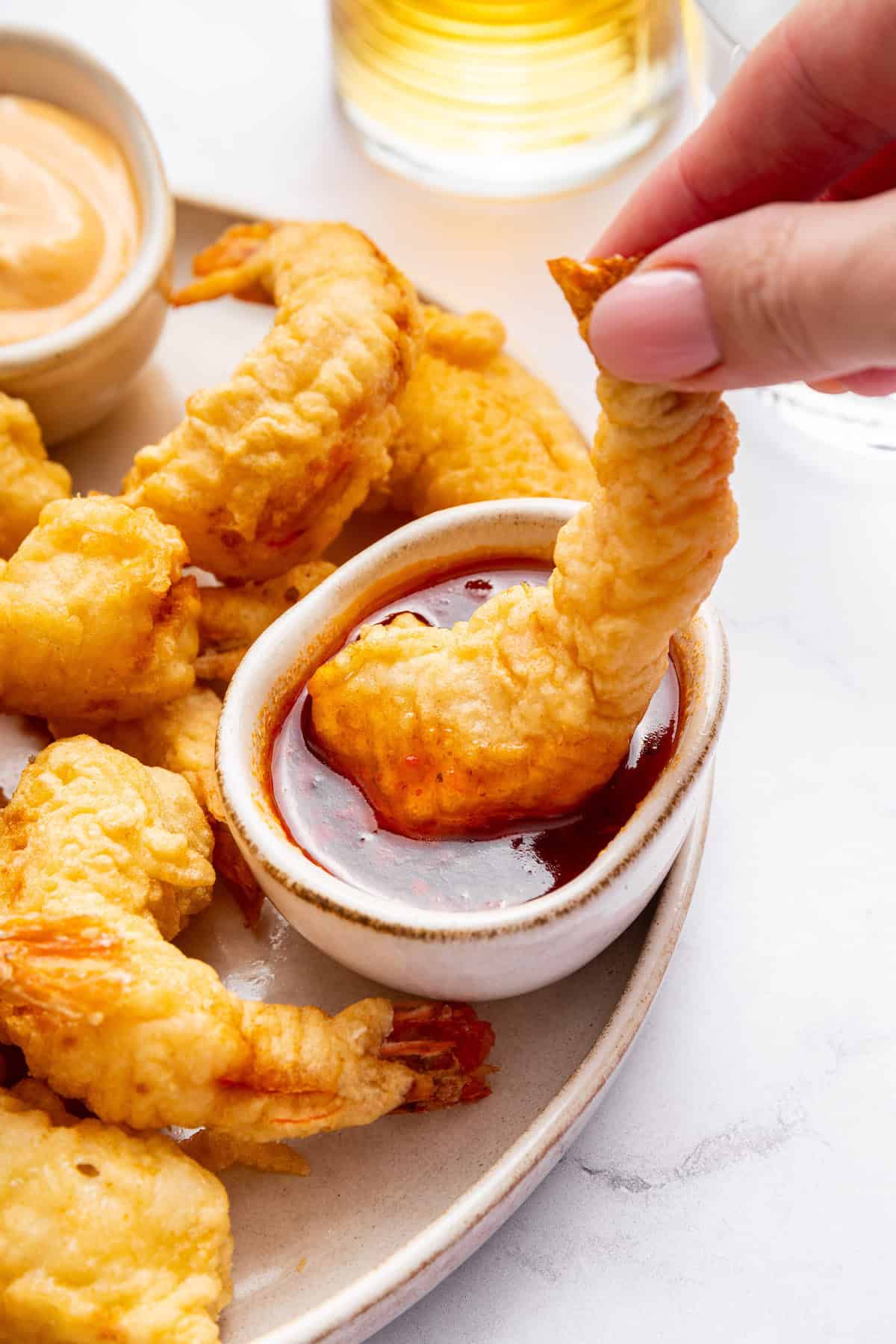 Hand dipping shrimp tempura into sauce