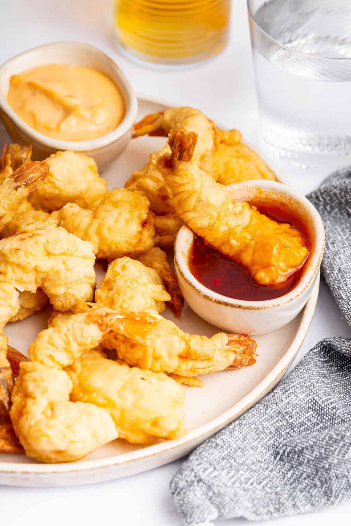 Crispy shrimp tempura on plate with bowls of dipping sauce
