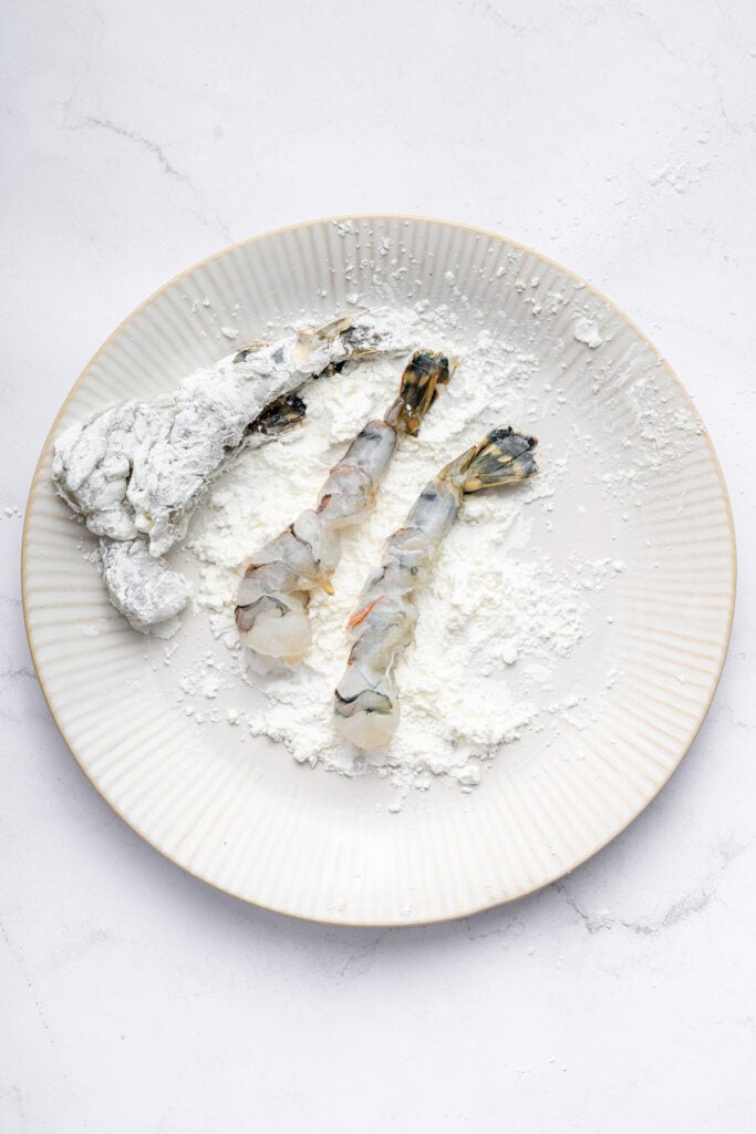 Coating shrimp in cornstarch on plate
