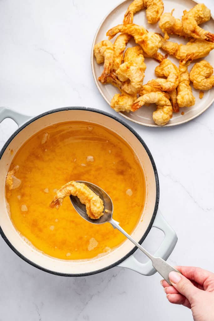 Using spoon to remove shrimp tempura from pot of oil