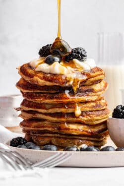Pouring maple syrup onto tall stack of cottage cheese pancakes