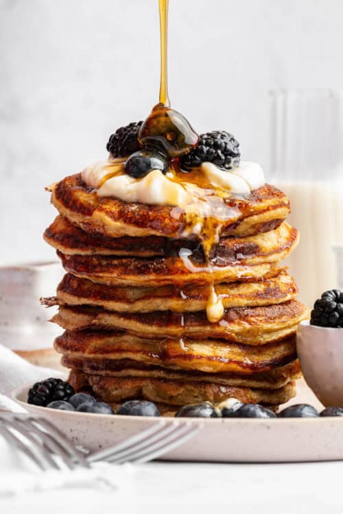 Pouring maple syrup onto tall stack of cottage cheese pancakes