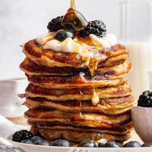 Pouring maple syrup onto tall stack of cottage cheese pancakes
