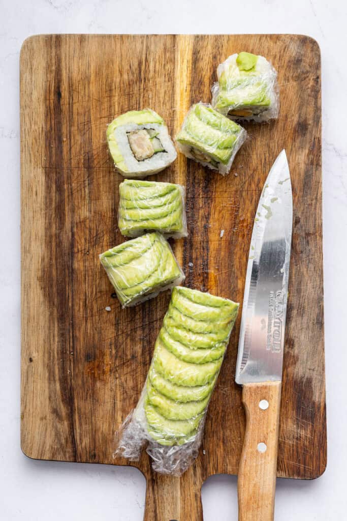 Overhead view of dragon roll sushi sliced on wood board with knife