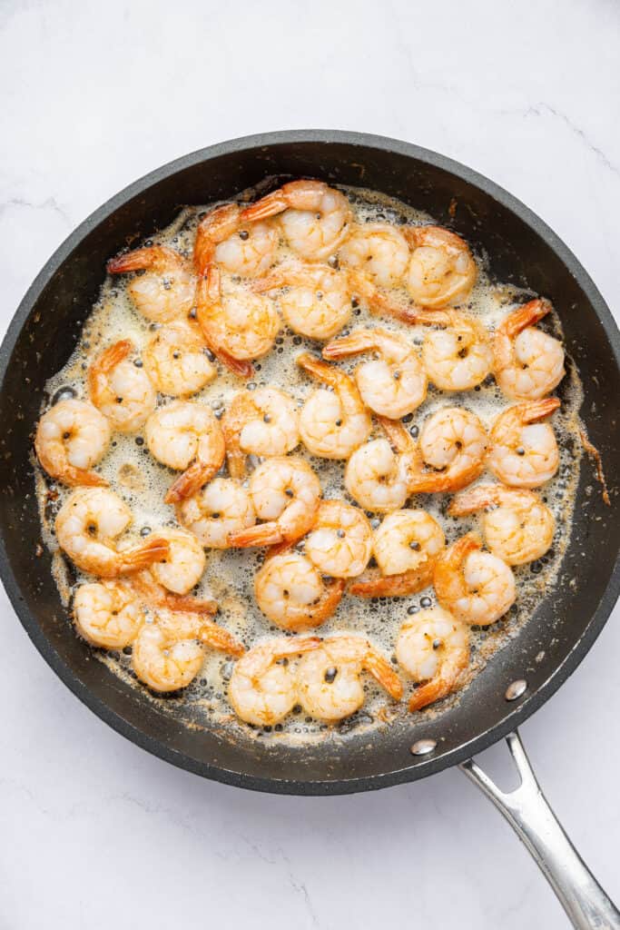 Overhead view of shrimp cooking in skillet