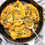 Skillet of lemon caper chicken with spoonful of sauce