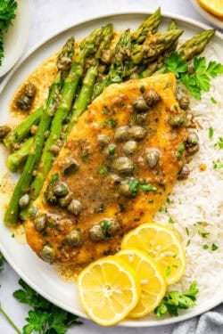Lemon caper chicken on plate with rice and asparagus