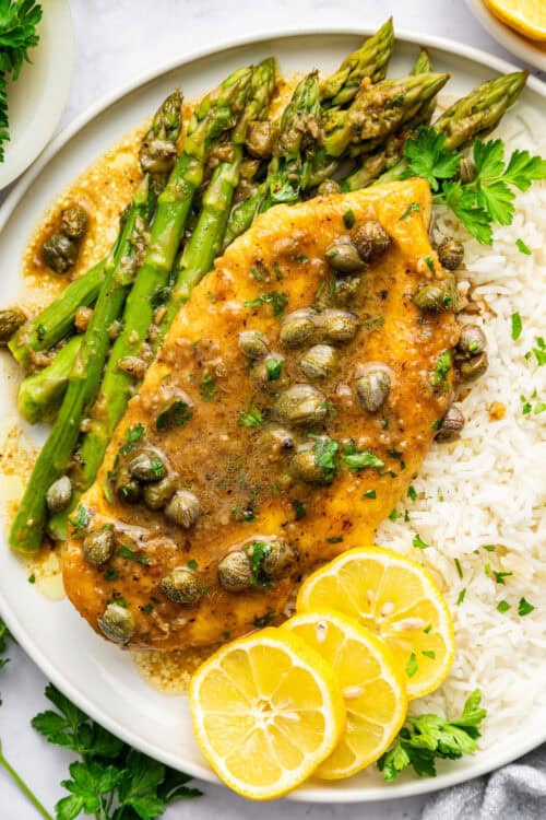 Lemon caper chicken on plate with rice and asparagus