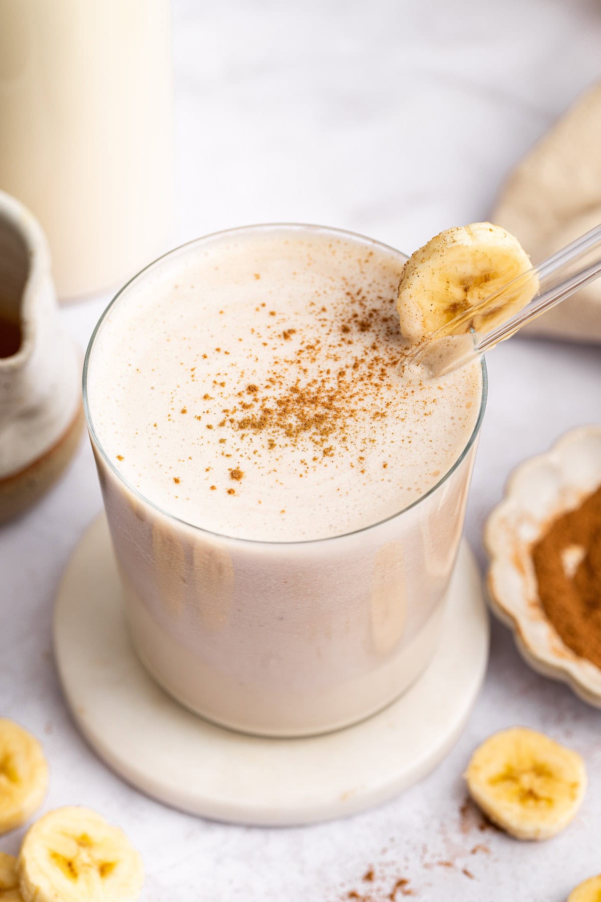 Top-down view of creamy banana milk in glass with cinnamon on top