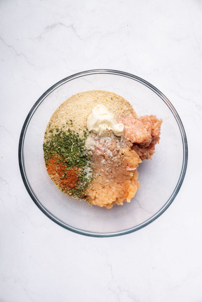 Overhead view of ingredients for chicken burgers in bowl before mixing