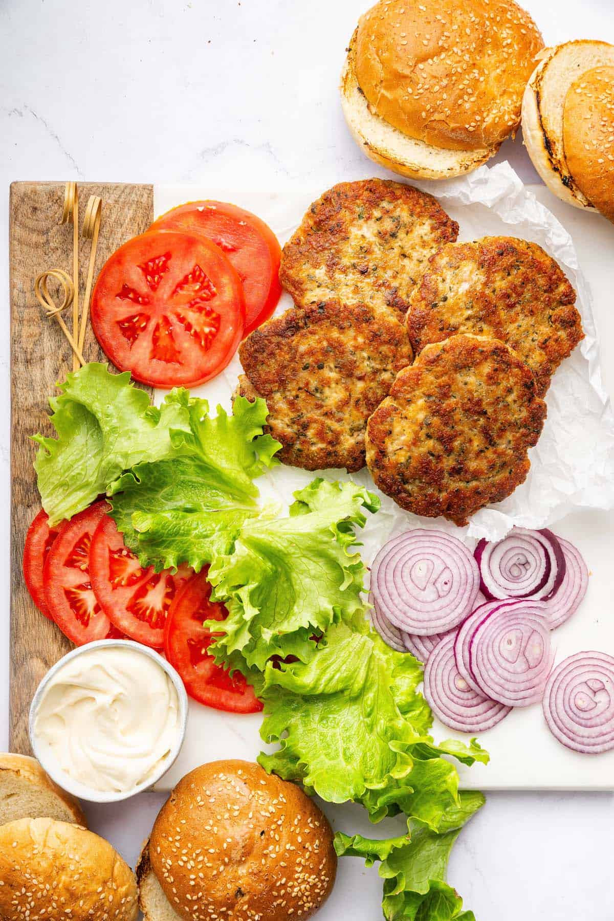 Overhead view of chicken burger patties, buns, and toppings