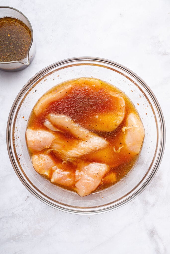 Overhead view of chicken in bowl of marinade