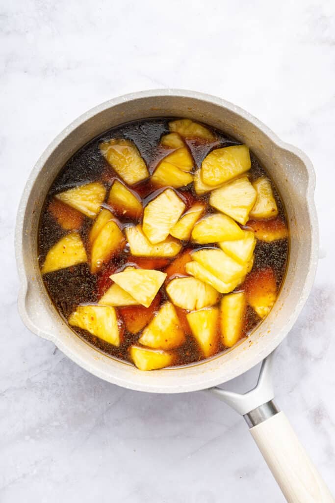 Overhead view of sauce and pineapple in pan