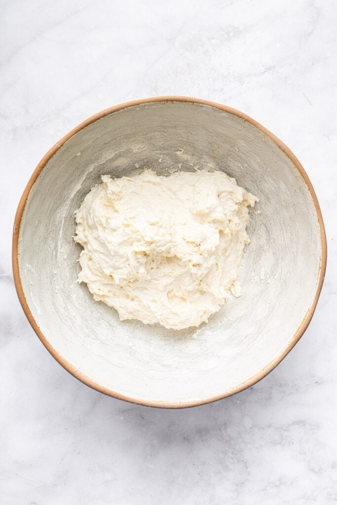 This Protein Pizza Crust is crisp and delicious, with Greek yogurt for a protein boost! Add your favorite toppings for a satisfying meal. Dough for protein pizza crust in bowl