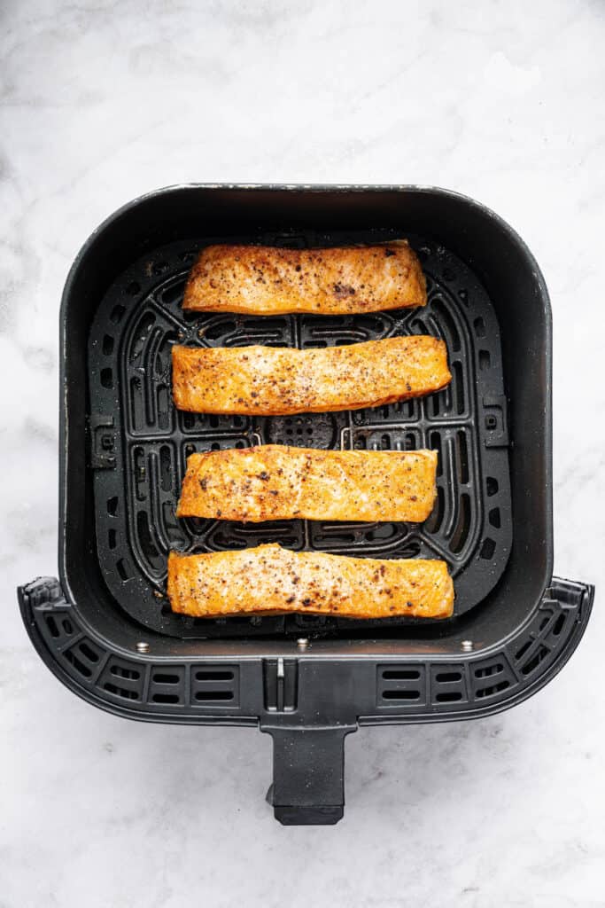 Yes, you can cook frozen salmon in the air fryer! It’s done in 25 minutes, ready for adding your favorite sauces, garnishes, and sides. Overhead view of frozen salmon fillets cooked in air fryer basket