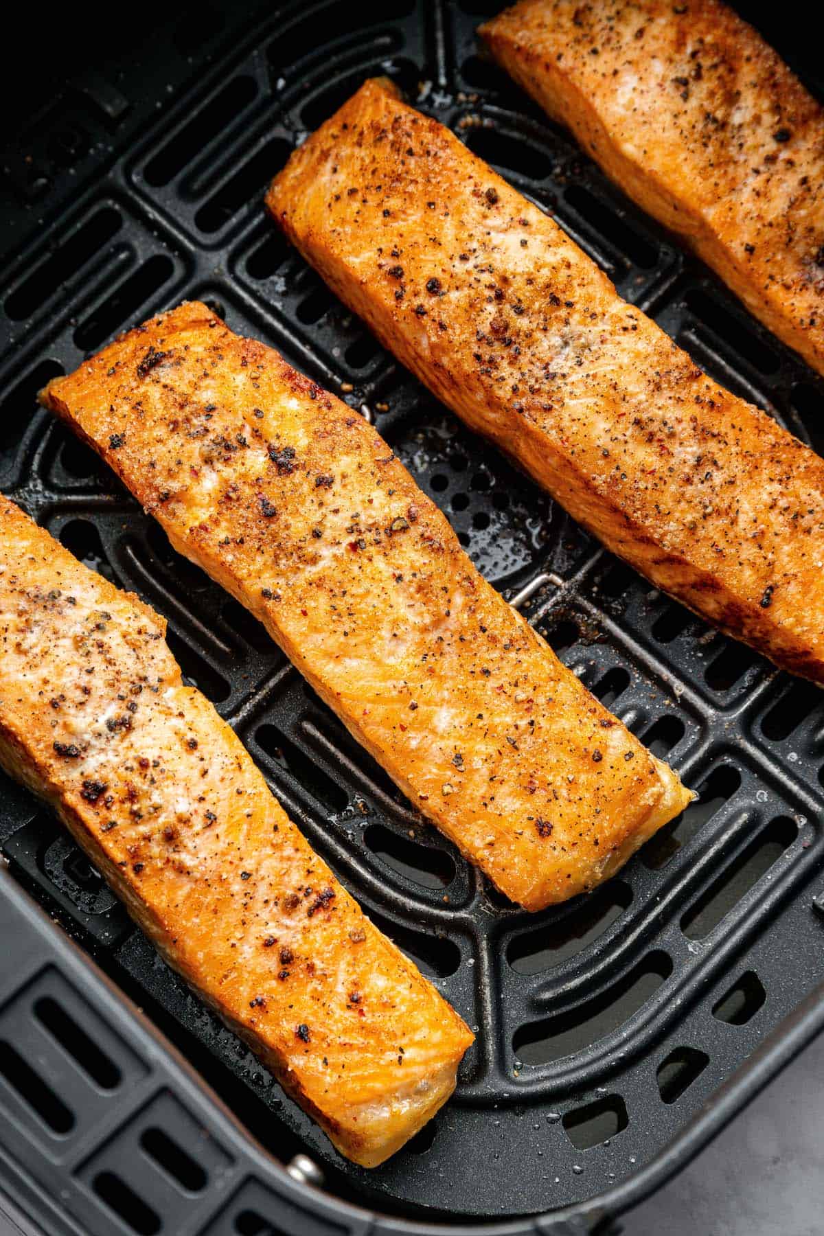 Yes, you can cook frozen salmon in the air fryer! It’s done in 25 minutes, ready for adding your favorite sauces, garnishes, and sides. Overhead view of frozen salmon fillets cooked in air fryer basket