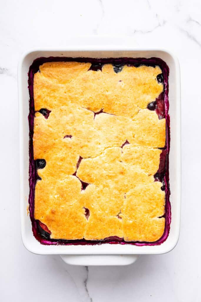 This blueberry peach cobbler recipe pairs two summer favorites in a jammy filling that’s baked with a buttery, flaky topping. So easy! Overhead view of blueberry peach cobbler in baking dish