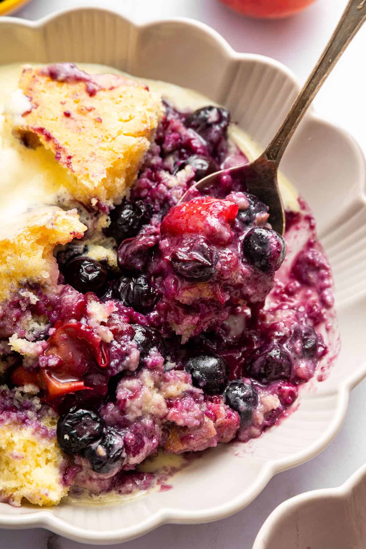 This blueberry peach cobbler recipe pairs two summer favorites in a jammy filling that’s baked with a buttery, flaky topping. So easy! Blueberry peach cobbler in bowl with spoon