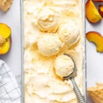 Overhead view of peach ice cream in loaf pan with ice cream scoop
