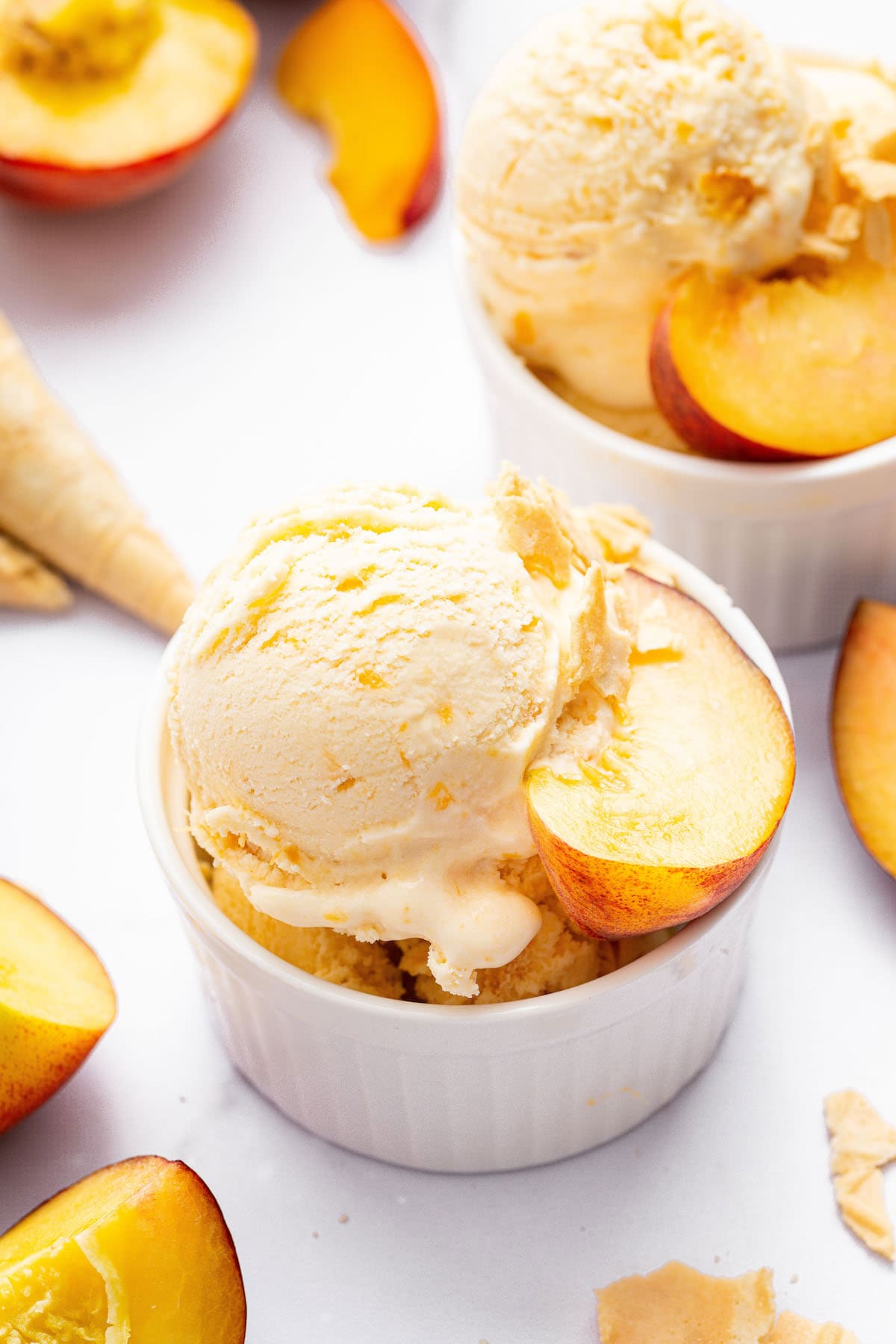 Top-down view of two bowls of peach ice cream with fresh peaches