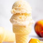 Two scoops of homemade peach ice cream in cake cone