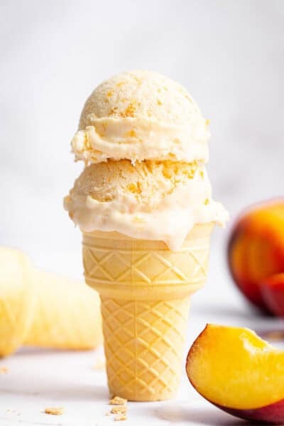 Two scoops of homemade peach ice cream in cake cone