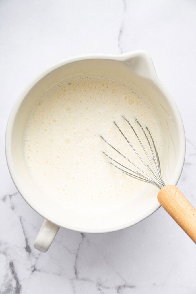 Overhead view of whisk in bowl with ingredients for ice cream