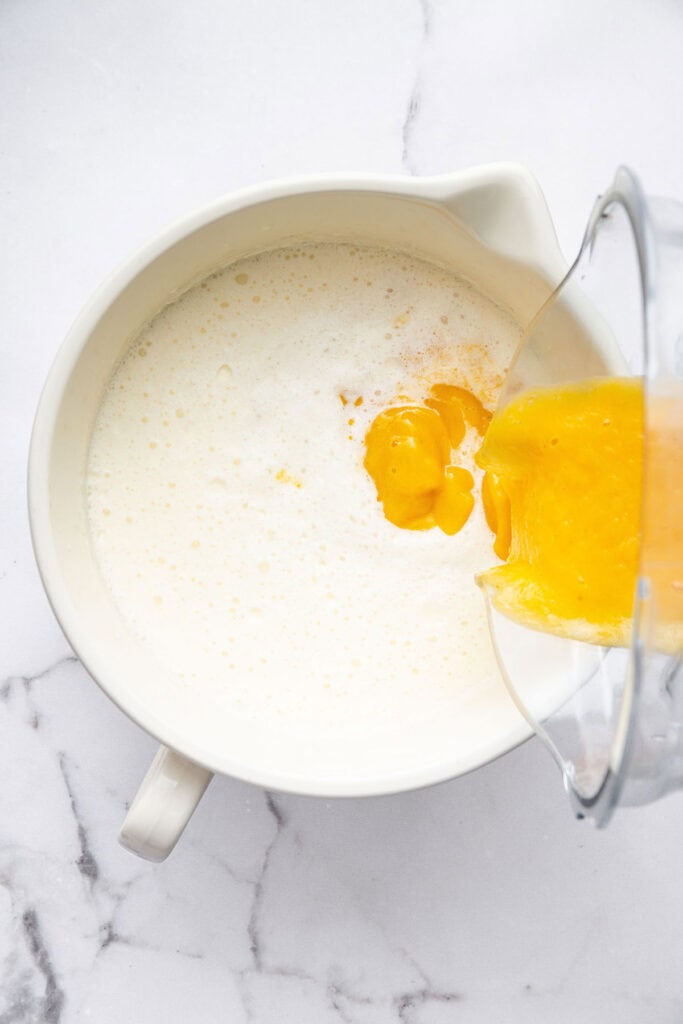 Pouring peach puree into bowl of ingredients for ice cream