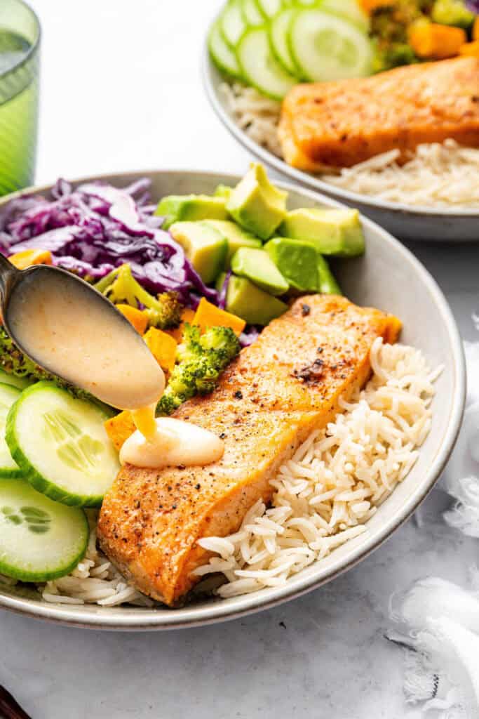 With flaky salmon, grains and veggies, this Salmon Power Bowl recipe is an easy meal prep option that will fuel you through your day! Drizzling sauce onto salmon power bowl
