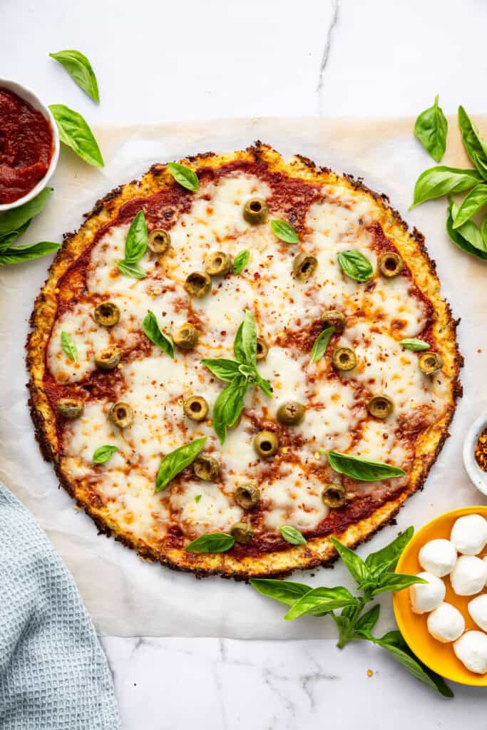 Overhead view of cauliflower crust pizza on parchment paper