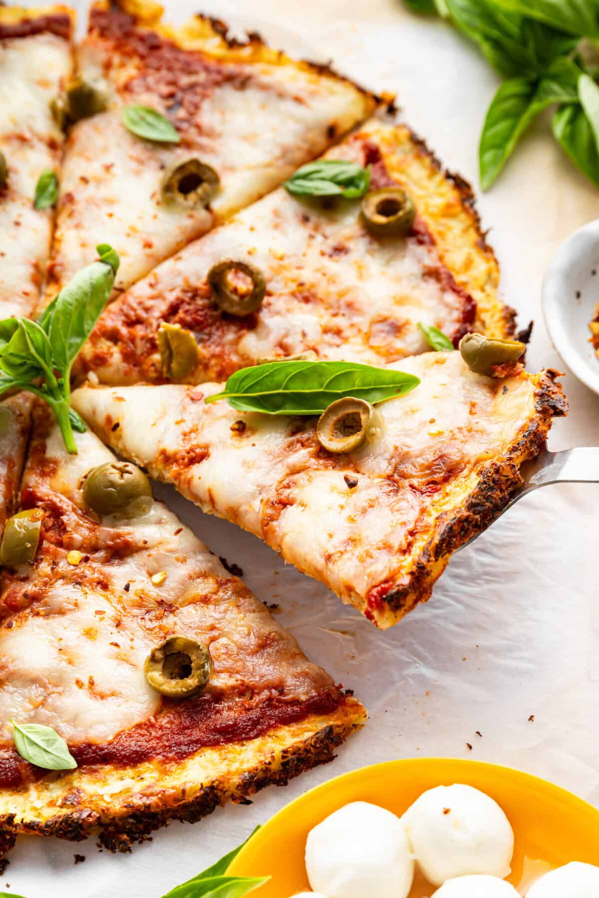 Pulling slice of cauliflower crust pizza away from rest of pizza