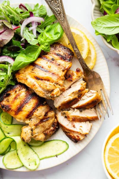 Closeup of Greek yogurt chicken on plate with fork and salad