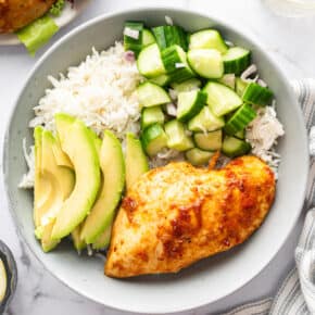 Bowl with white rice, harissa honey chicken, cucumber, and avocado.