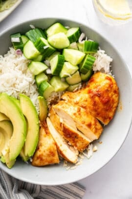 Bowl with harissa honey chicken, white rice, cucumber, and avocado.